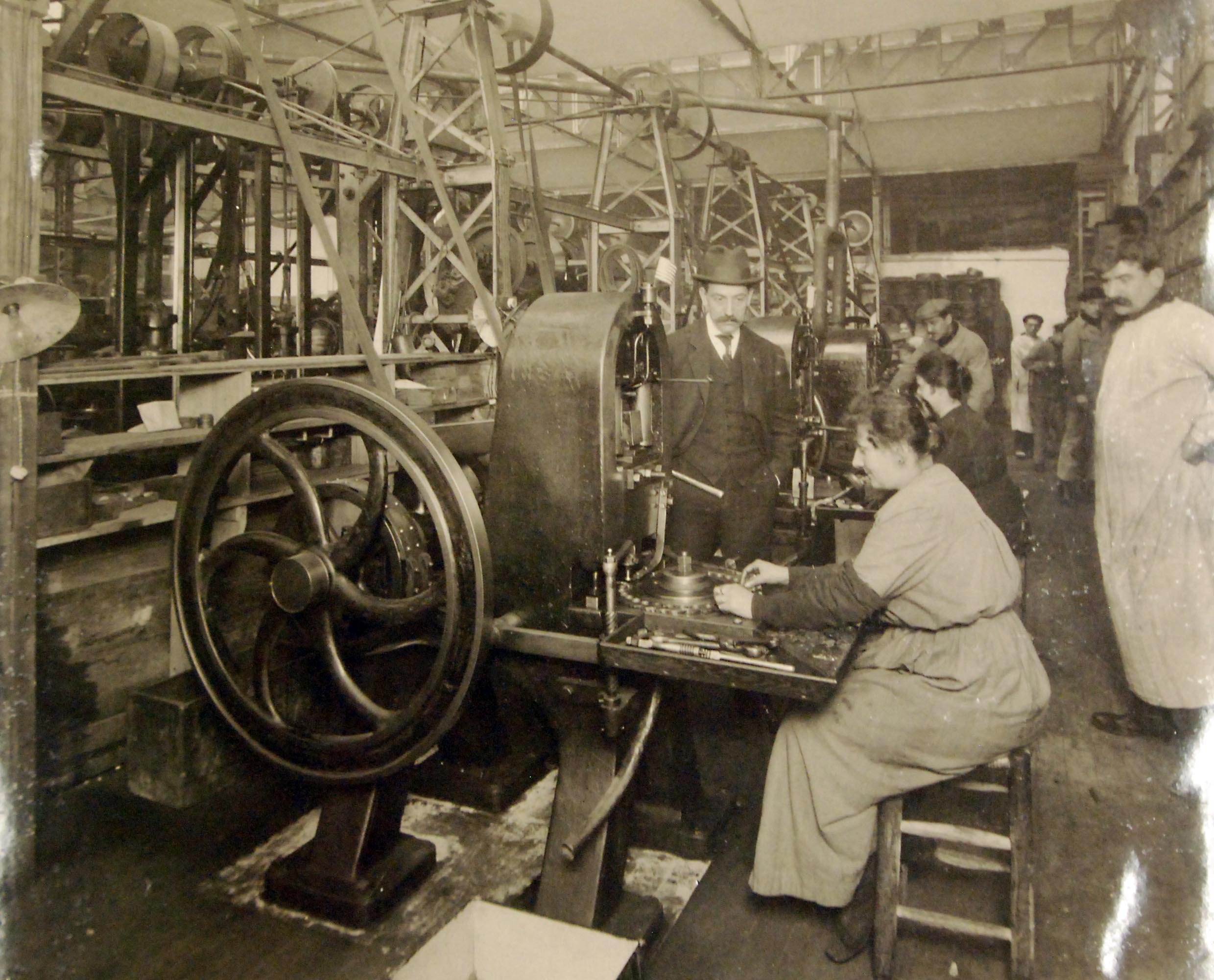 Workers operate a historical button stamping machine inside the Henri Jamorski factory in Paris, 1919