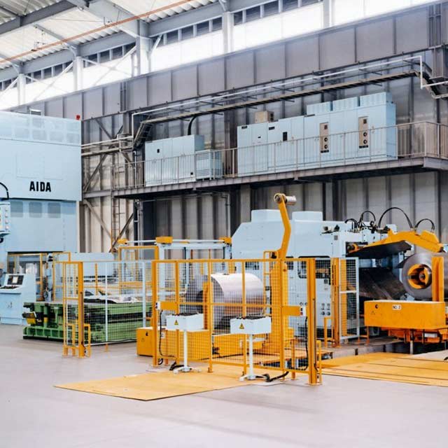 Industrial coil feeder line with press automation equipment arranged inside a manufacturing facility