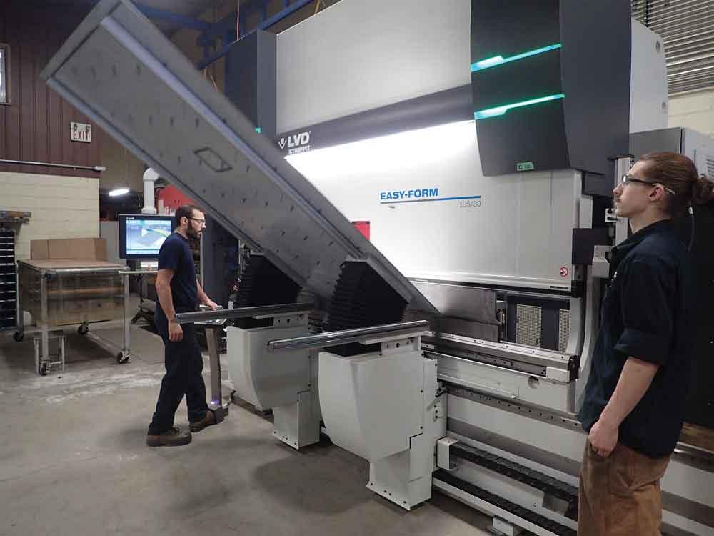 Operator bends a long sheet-metal panel on an LVD Strippit CNC press brake