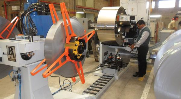 Technician feeds sheet metal strip into a leveler and looping area during press line changeover