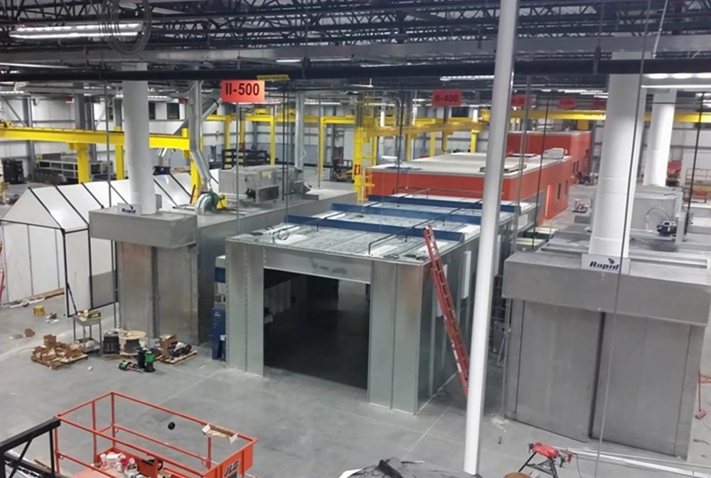 Industrial powder-coating equipment finishing fabricated metal parts on a production line