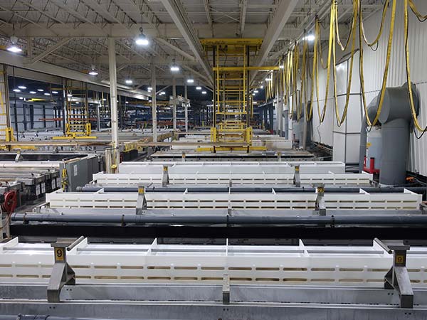 Automated anodizing production line with overhead hoists moving aluminum loads through processing tanks