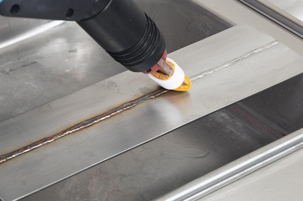 Automated arm electrochemically cleans a stainless steel weld joint during industrial passivation treatment