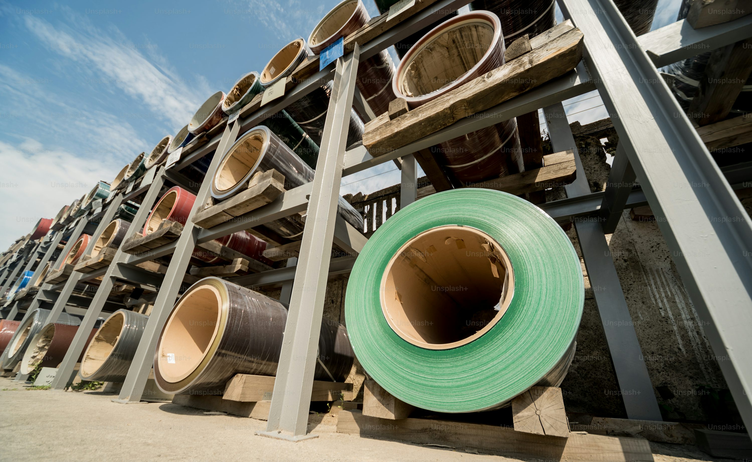 Rows of colored steel coils stored on metal racks at a metalworking manufacturing facility