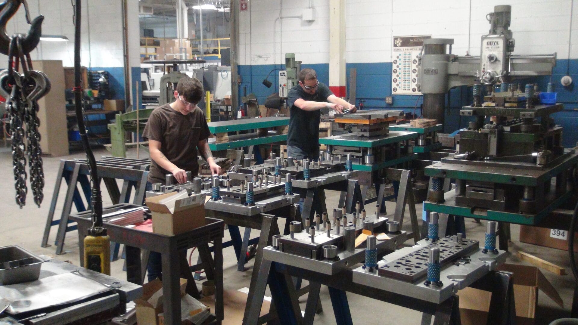 Toolmakers maintaining stamping die components on benches in a production workshop