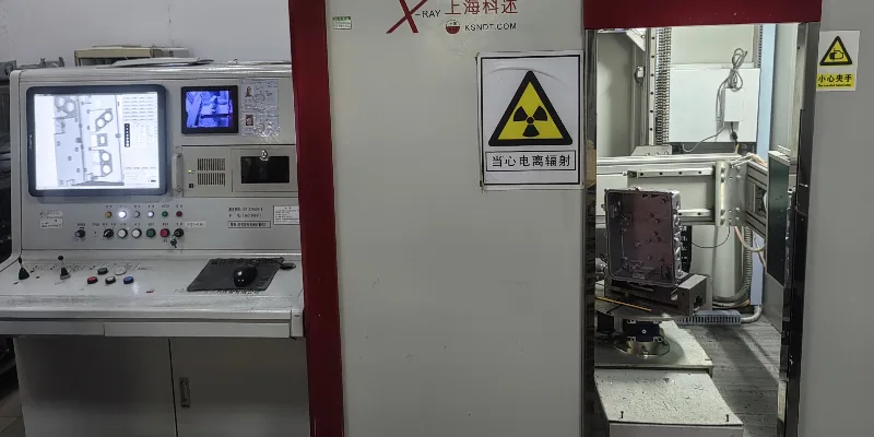 Technician measuring a machined aluminum housing with digital calipers on a factory inspection bench
