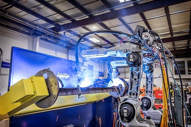 Robotic welding cell joining a fabricated metal component inside a factory
