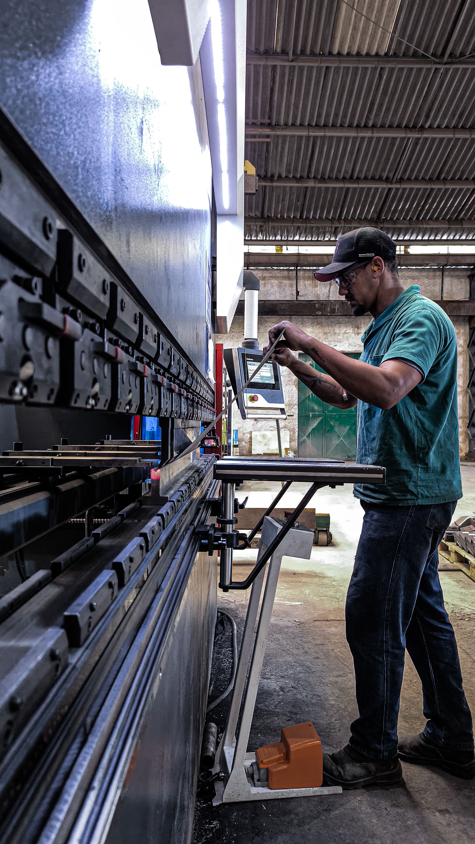 Operator forming sheet metal on a long industrial press brake inside a fabrication workshop