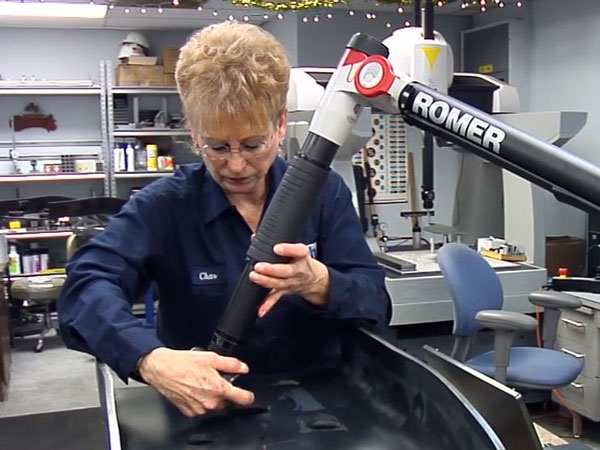 Technician uses a ROMER portable CMM arm to inspect a formed metal part in a manufacturing facility
