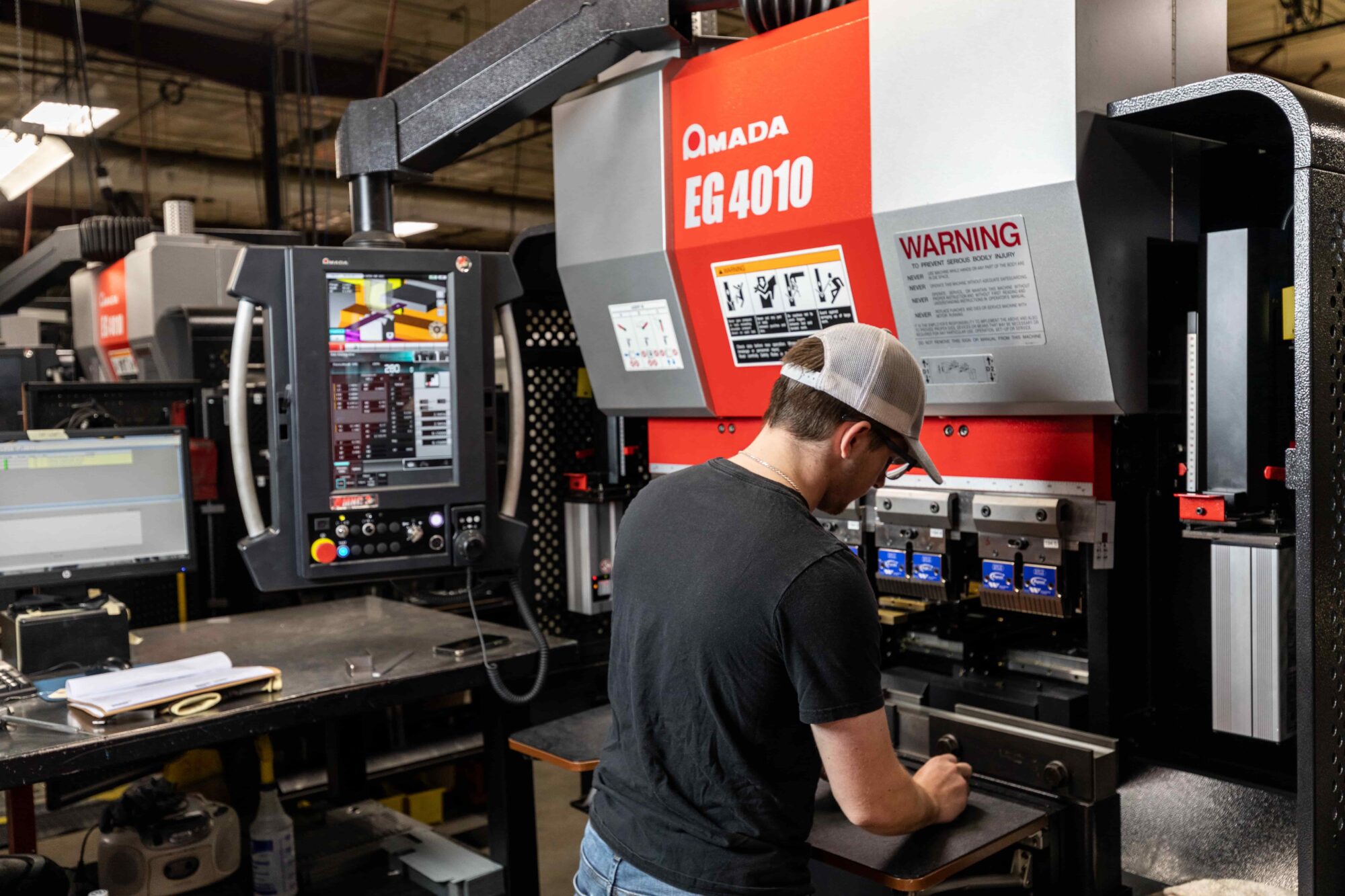 Operator forming sheet metal at a CNC press brake in a fabrication shop