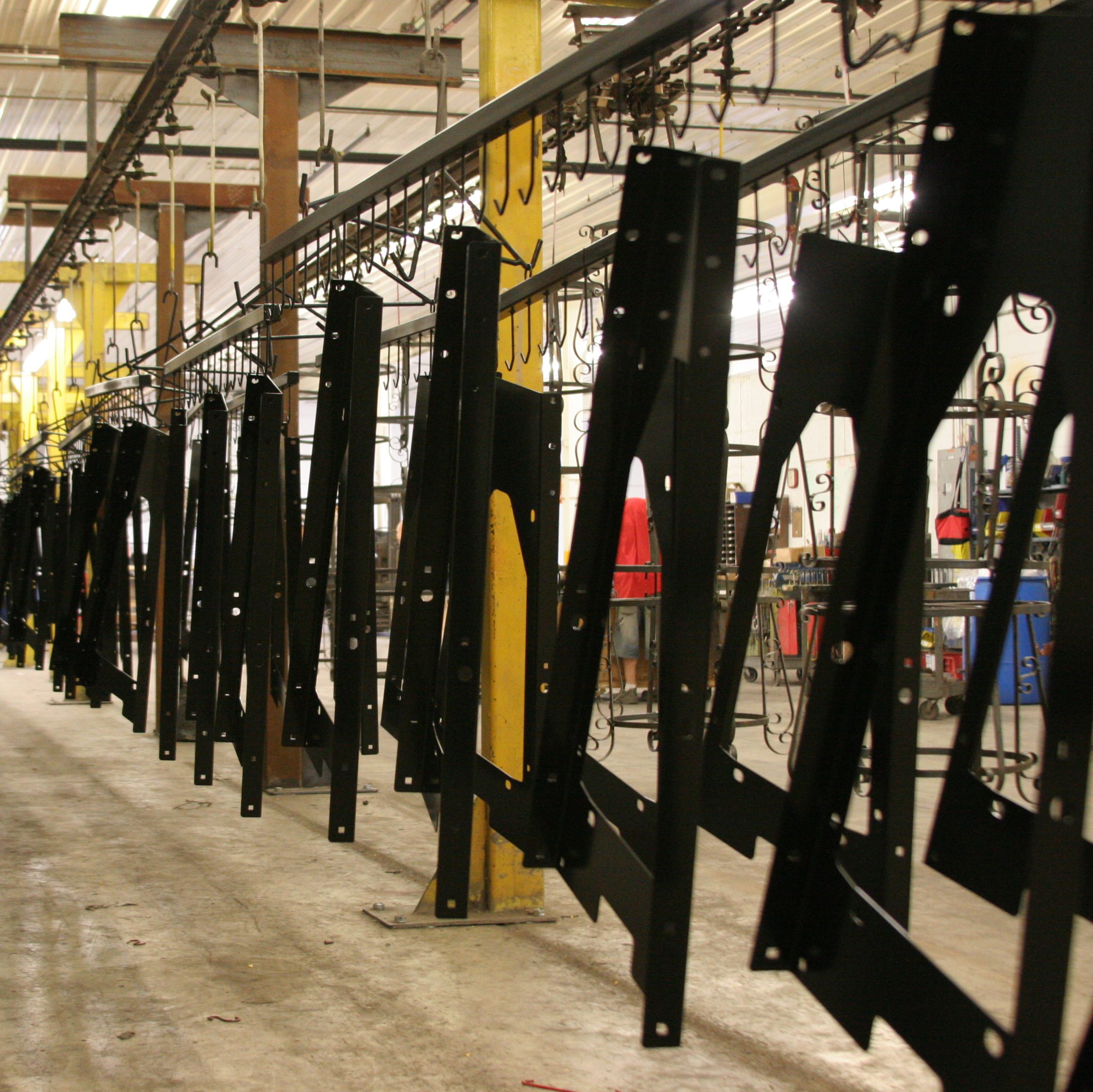 Finished metal components moving through an automated industrial powder-coating line