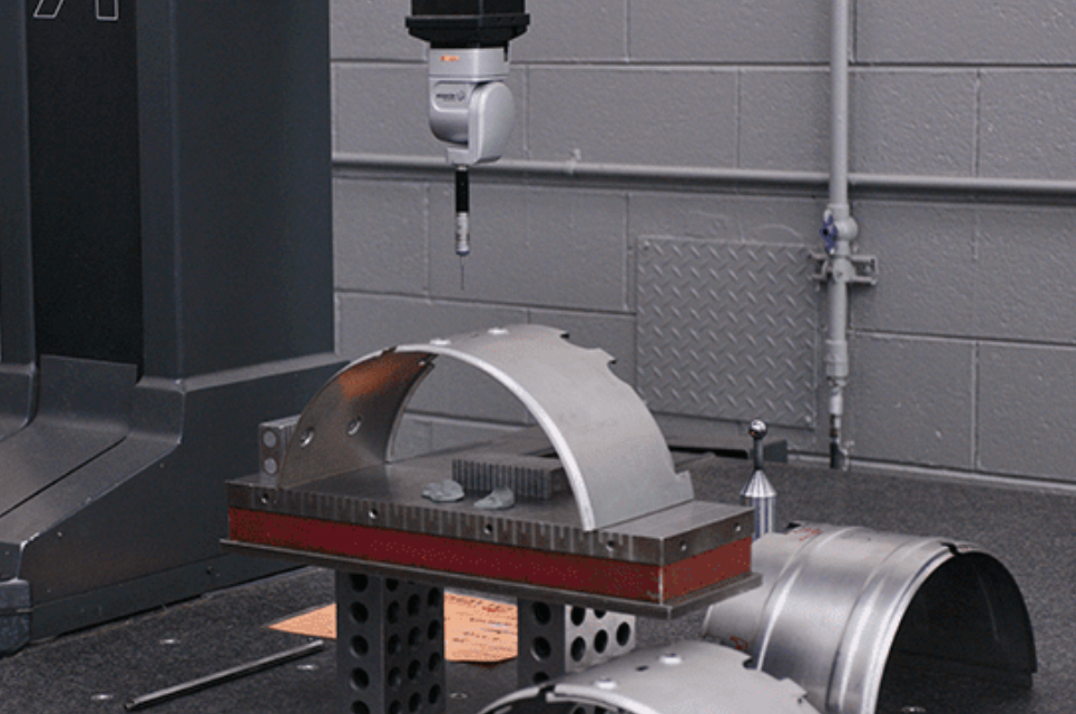 Quality inspector measuring a sheet-metal component beneath a coordinate measuring machine