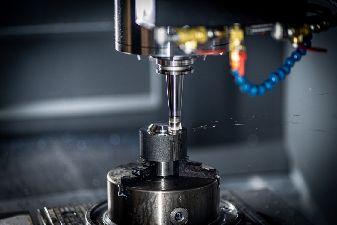 Close-up CNC milling spindle machining a metal part inside an industrial manufacturing cell
