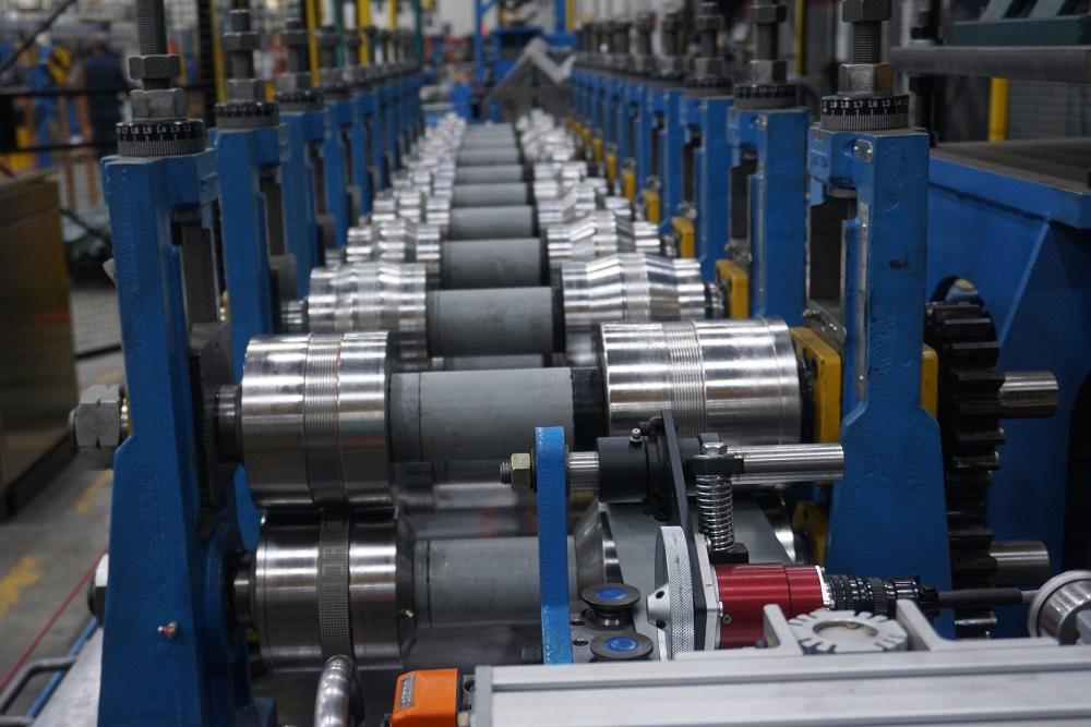 Roll-forming mill with multiple steel rollers progressively shaping a continuous metal strip